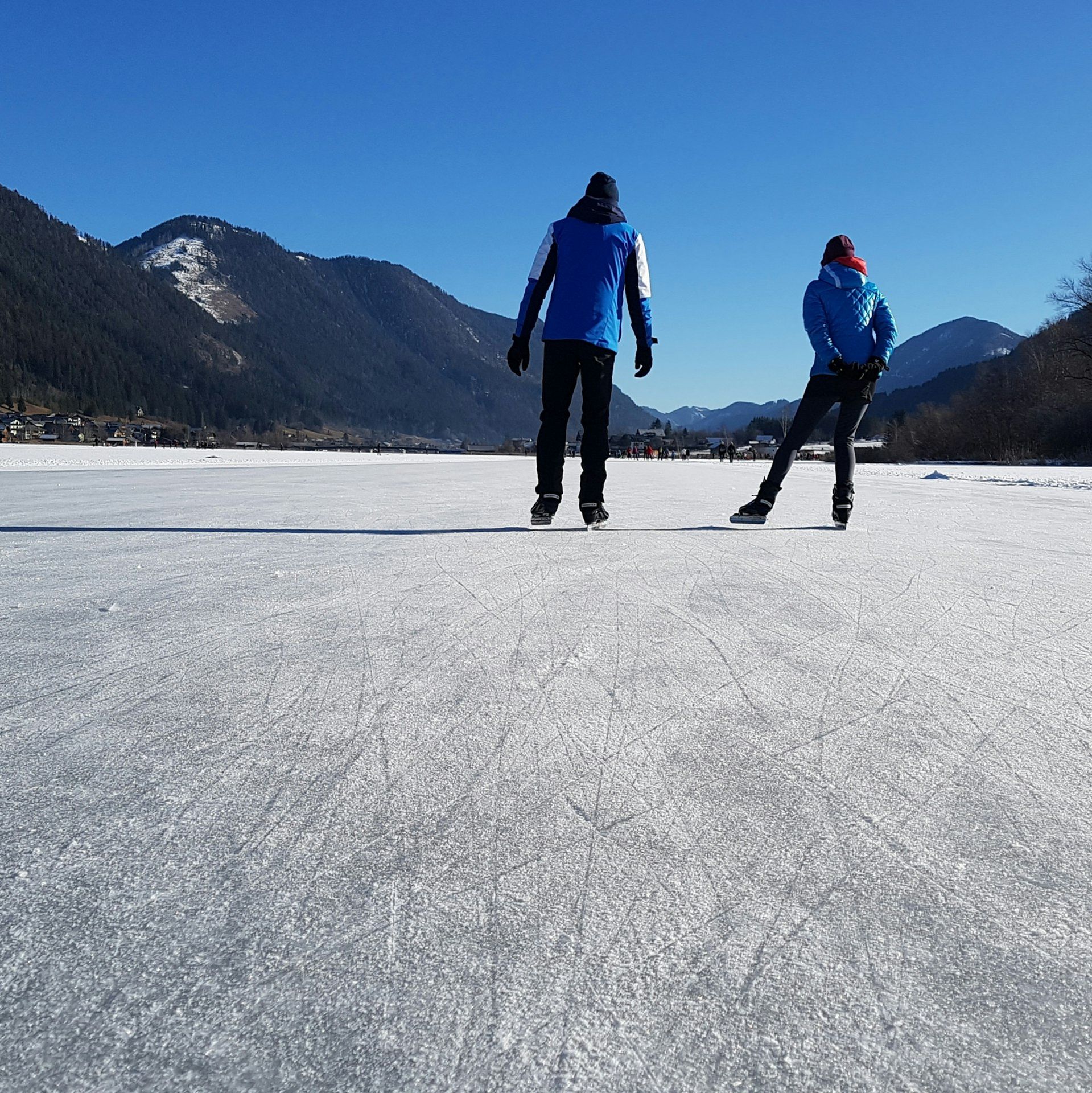 Two people ice skating on a frozen lake